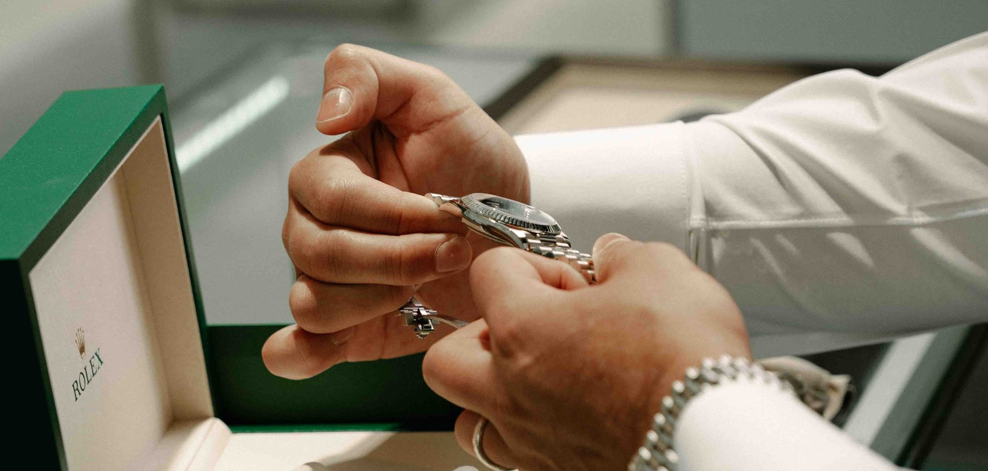 A Rolex Datejust presented by hand over its open box at the boutique counter