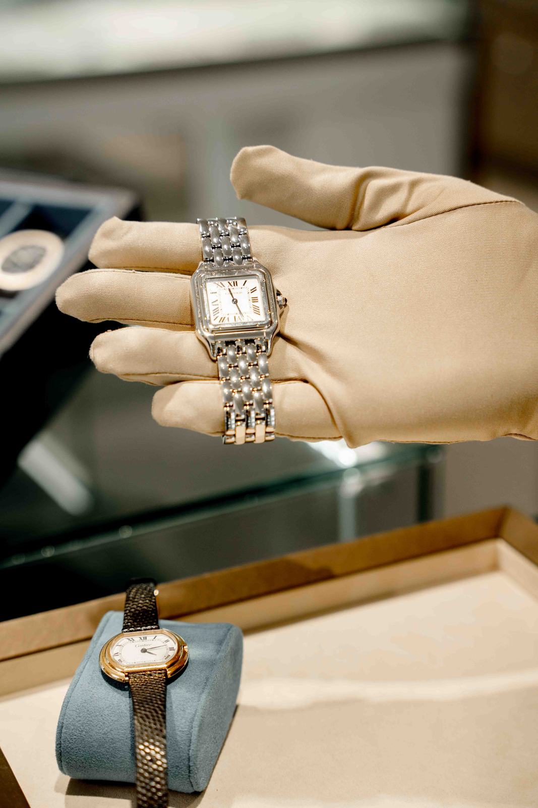 A gloved hand presenting a vintage Cartier watch above a tray at Creation Paul H