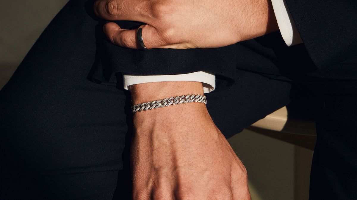 Pavé curb bracelet and ring on stacked hands, navy suit