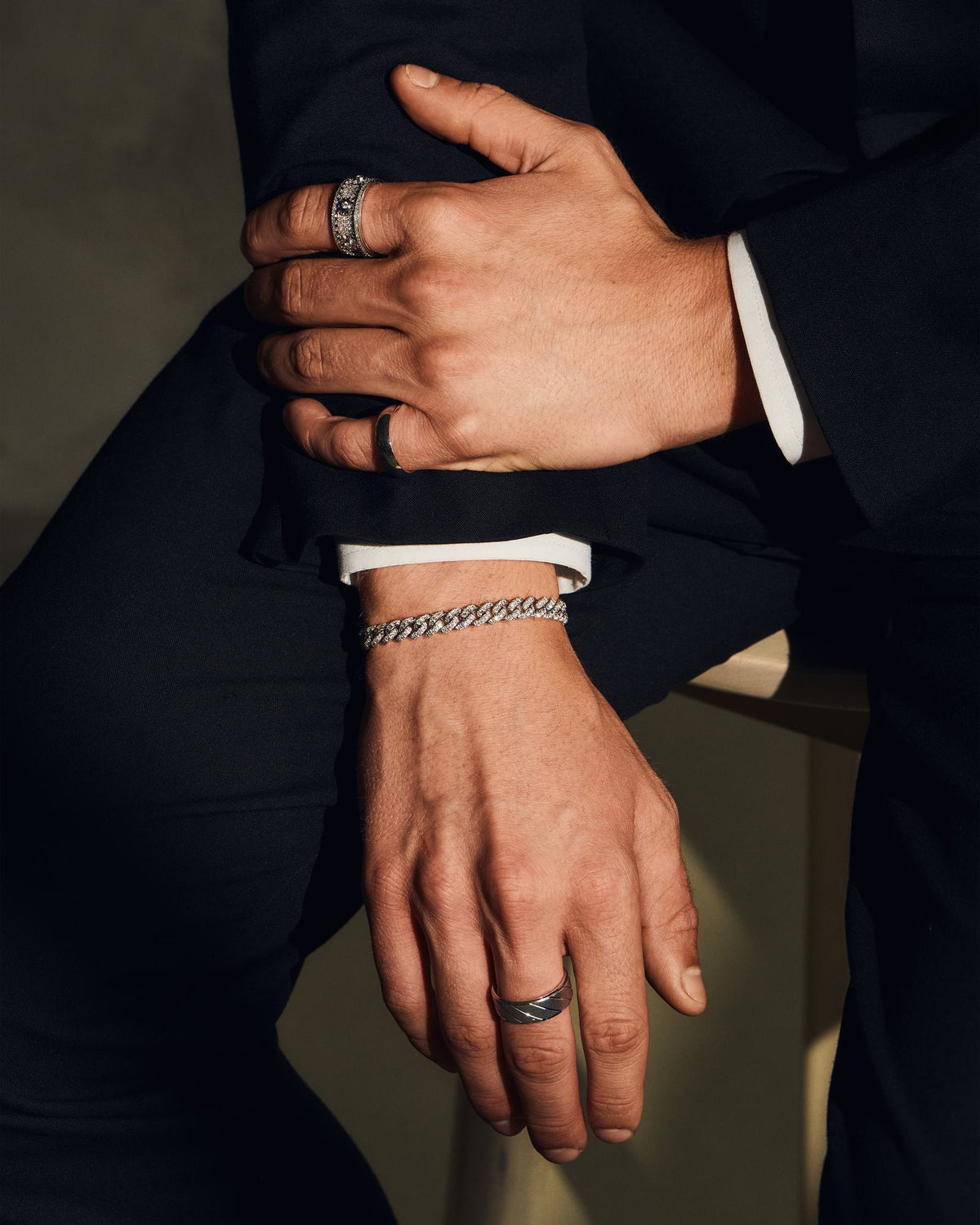 Stacked hands wearing gold rings and a pave bracelet