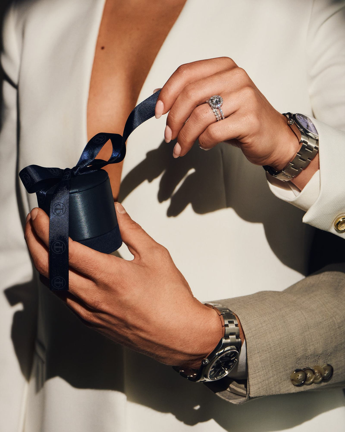 Hands untying the navy Creation Paul H ribboned gift box