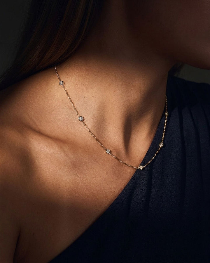 Bezel-set diamond station necklace worn at the collarbone. Representative made-to-order image